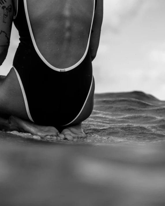 a woman is sitting in the water looking into the ocean