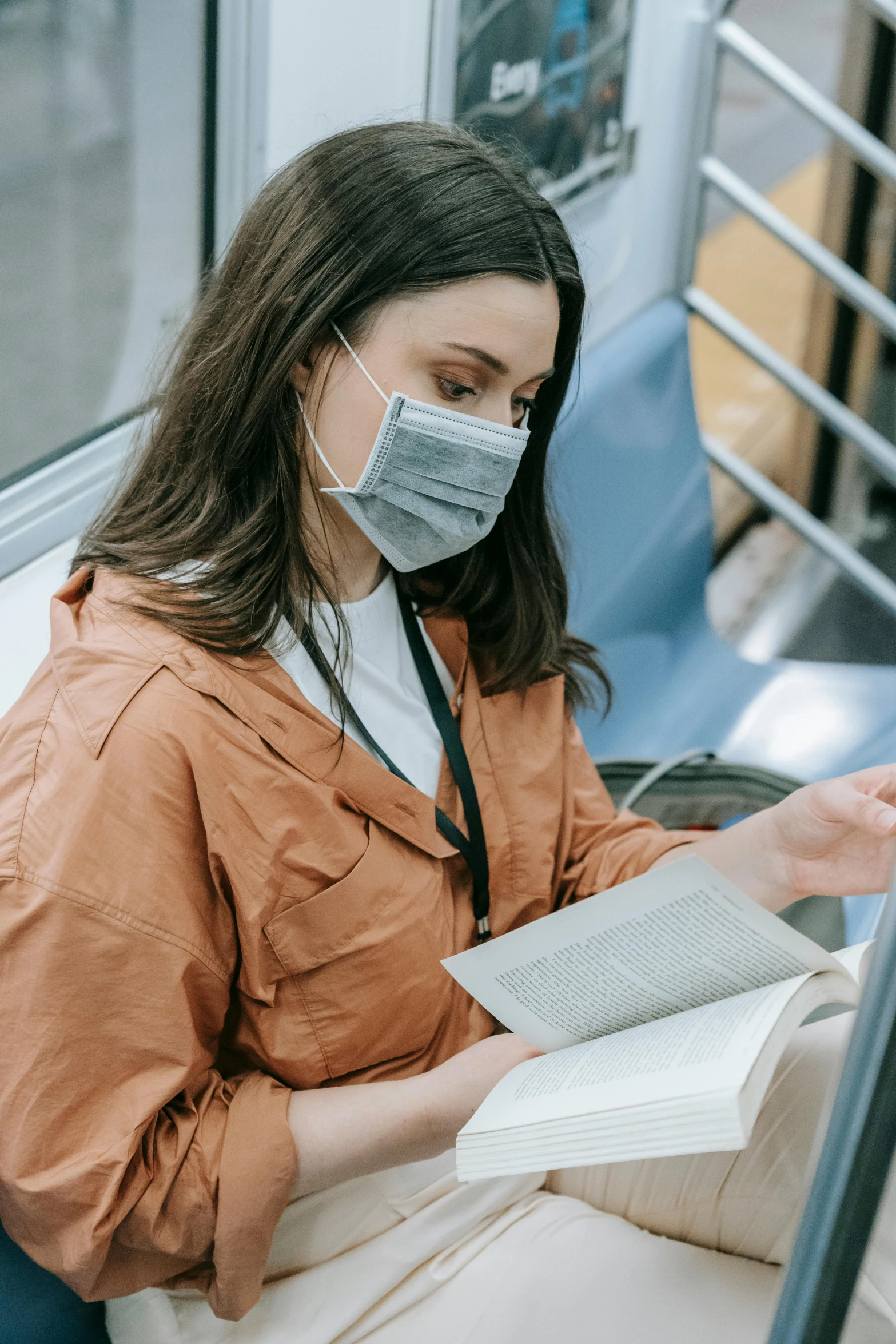 a person on a train wearing a mask reading a book