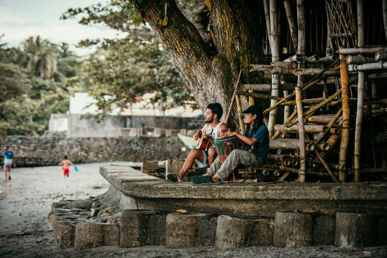 two people sitting on a bench under a tree