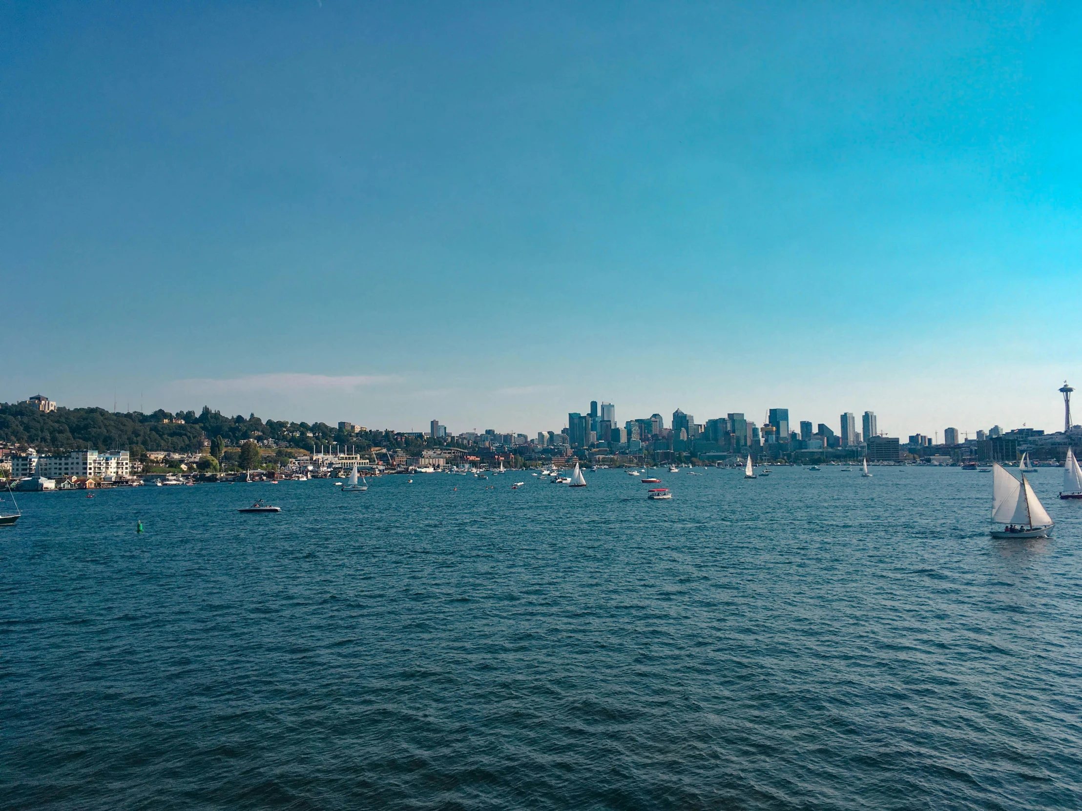 several boats floating in the water by some large buildings