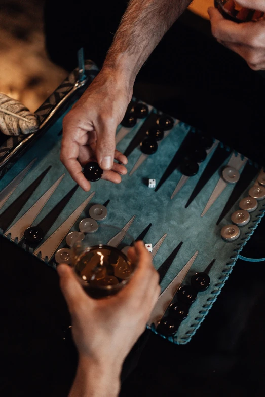 two hands are touching over a game with cups