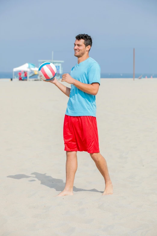 a man standing in the sand holding a ball