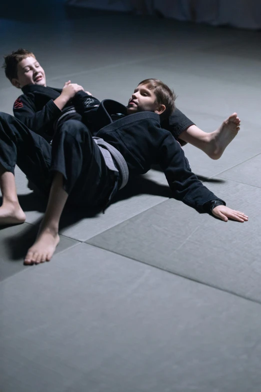 two young s in black karate attire performing on the ground