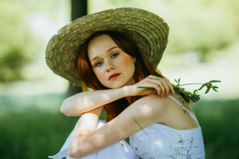 a young red headed girl wearing a straw hat