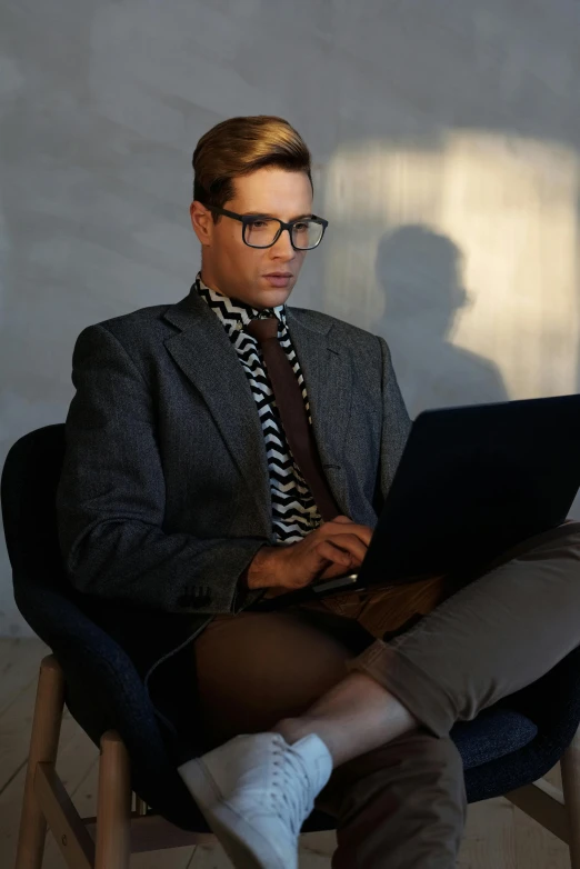 a man in suit and tie sitting down with a laptop computer
