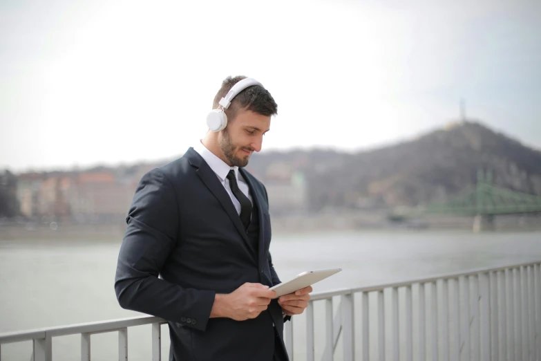 a man in a suit holds his tablet while looking at it
