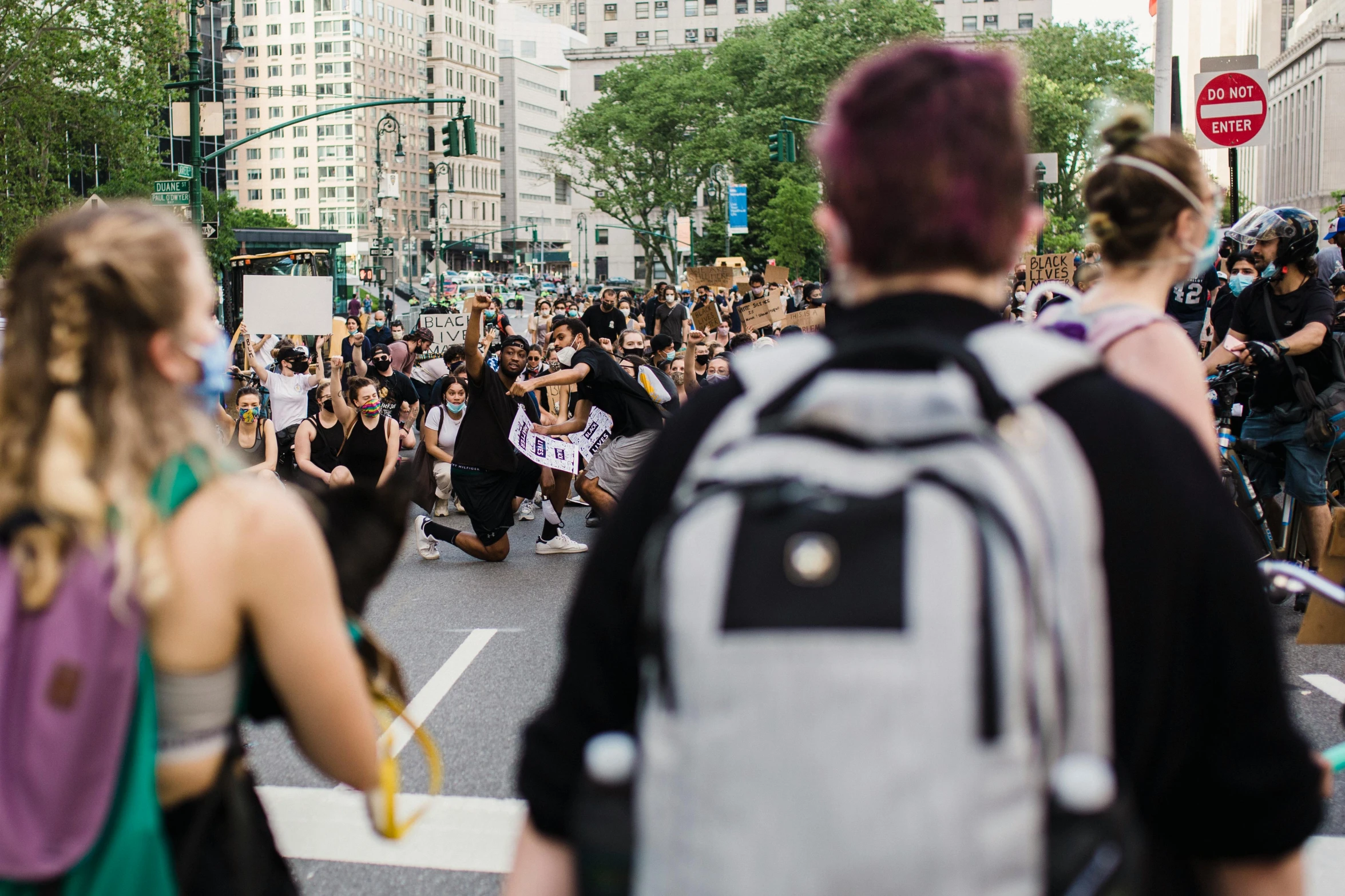 several people standing in the street with their arms up and backpacks on their shoulders