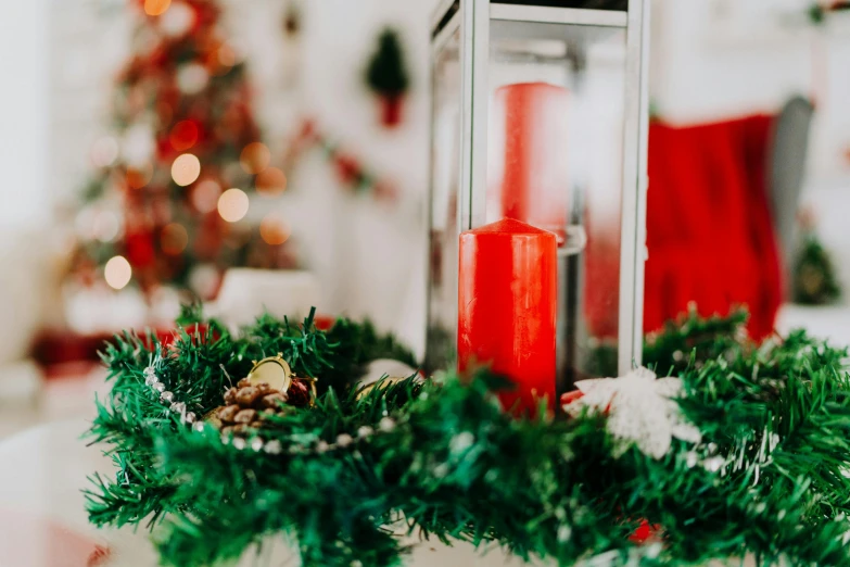 a lighted candle next to a festive wreath