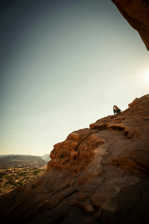 a man sitting on top of a rock looking out over a valley