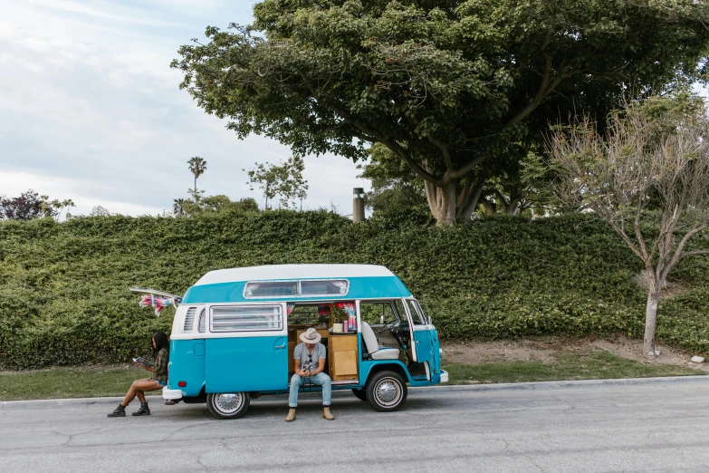 two people sitting next to an rv on the side of a road