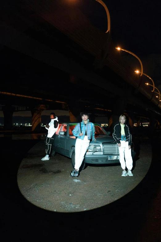 three people standing near a car at night