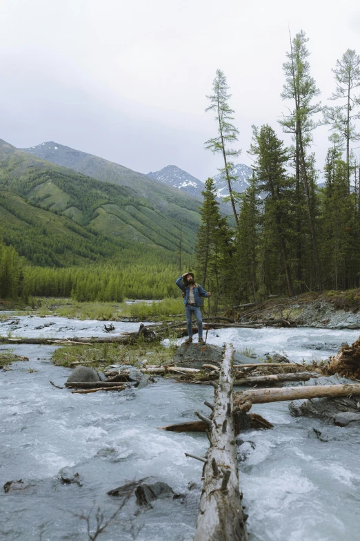 two people standing by the water near logs