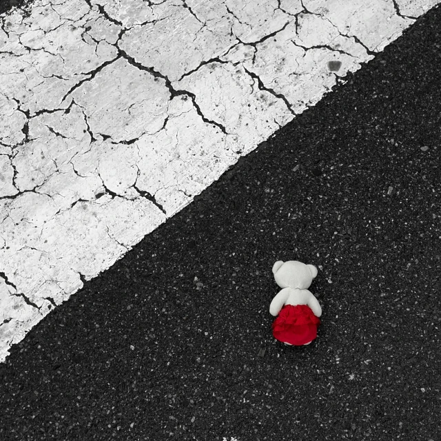 a teddy bear sitting on the pavement near a street