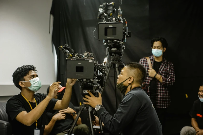 several people with face masks standing around a camera