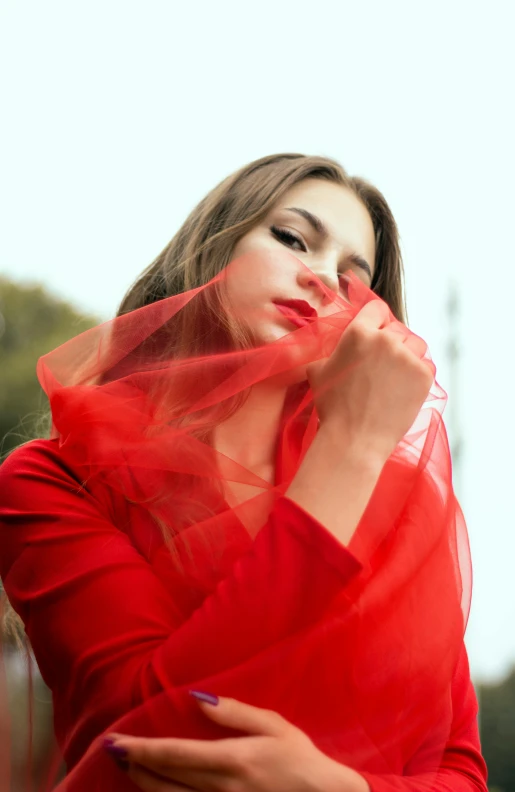 a young woman wearing a red shirt and veil