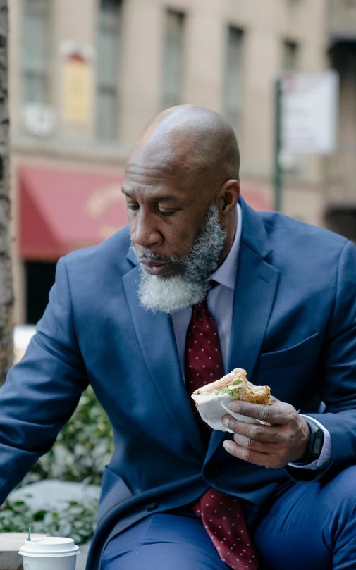 a man with beard and suit eats outside