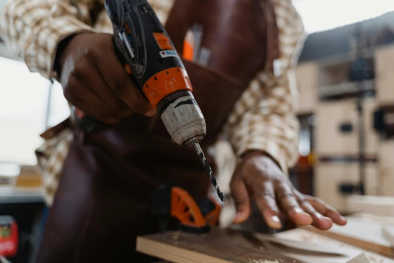 a man holding a drill as he works on wood