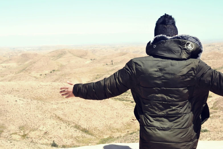 a person wearing a jacket looks out over the desert