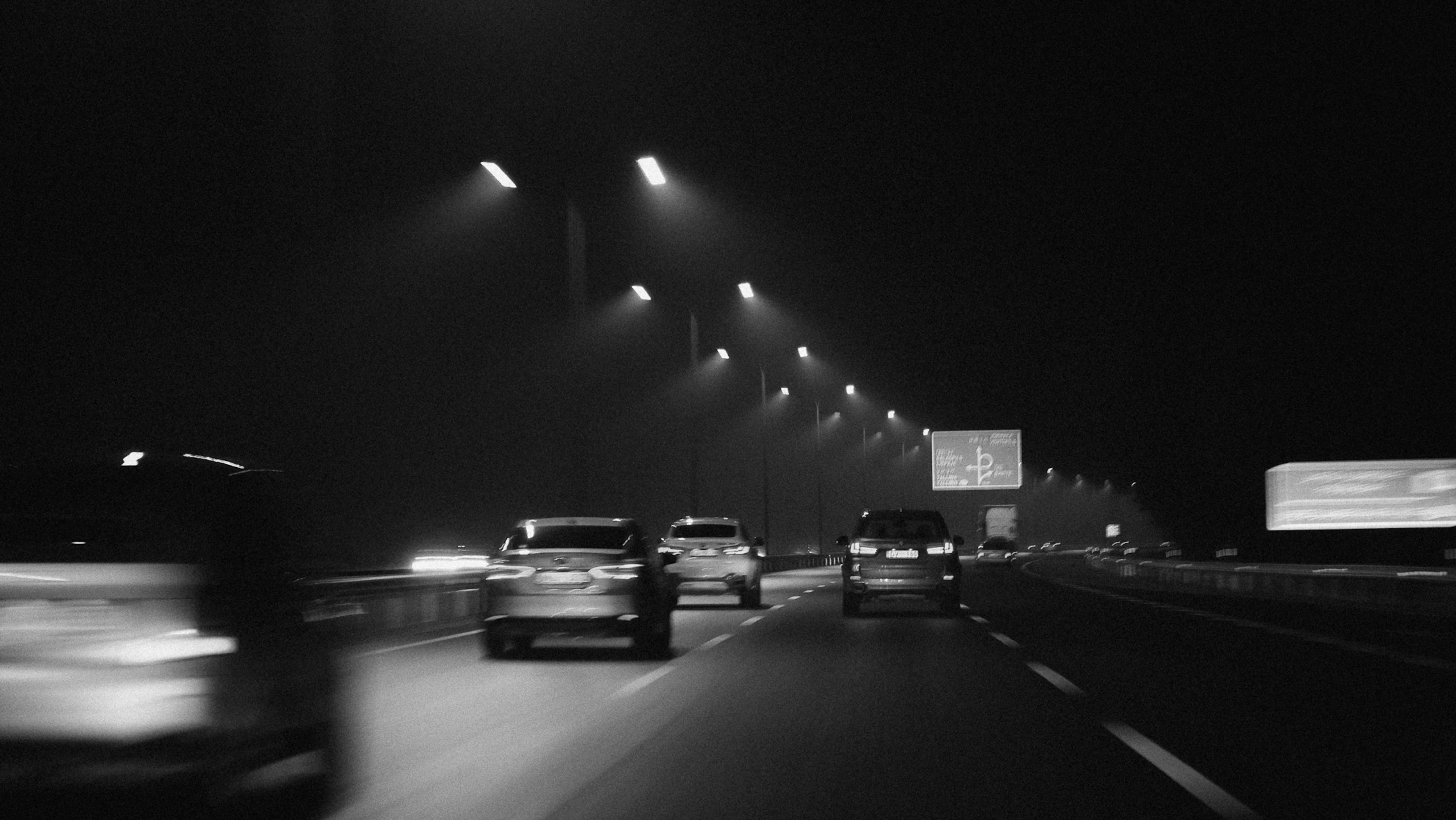 cars driving down the highway in the dark at night