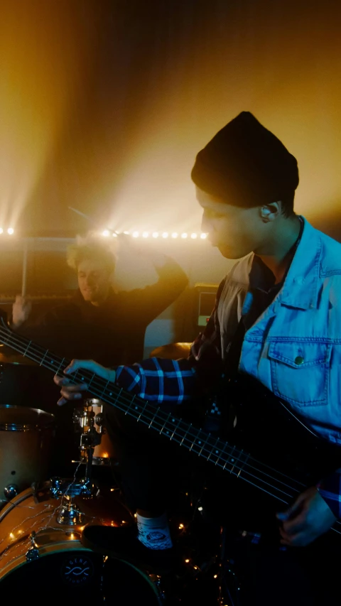 two men are playing bass guitar in a darkened room