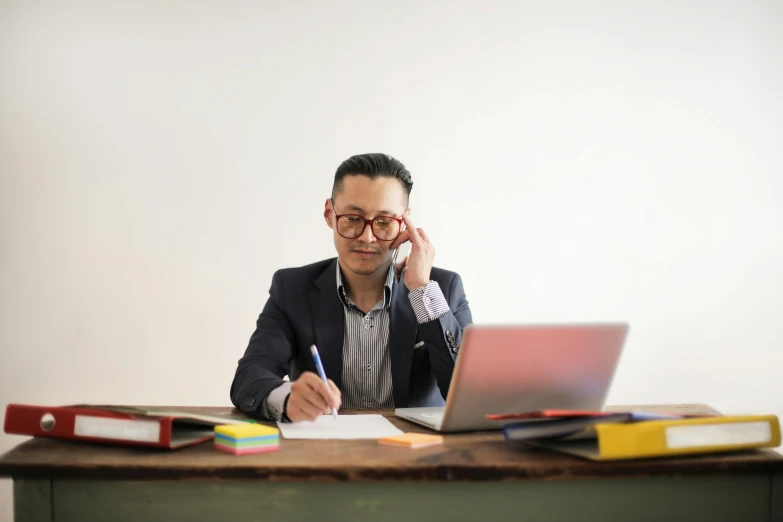 the man is talking on his cell phone by his computer