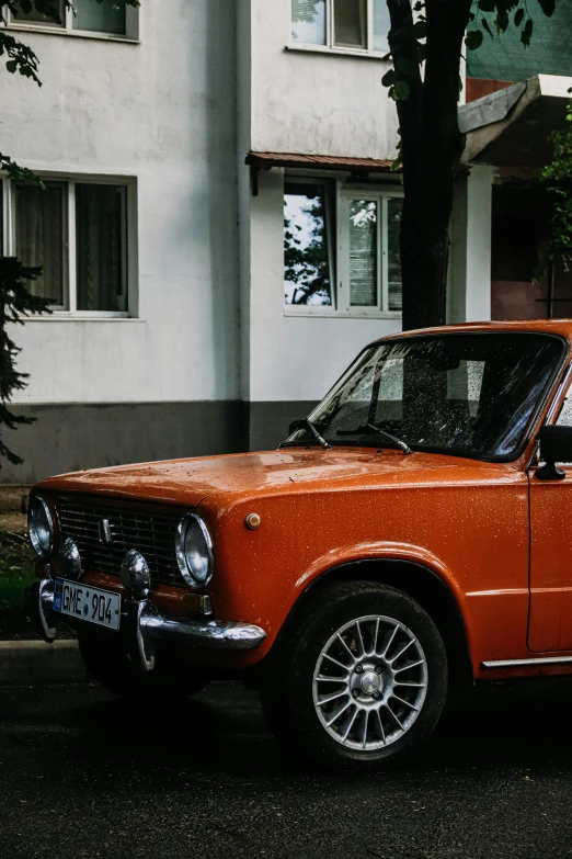 an old orange and white car parked in front of a white building