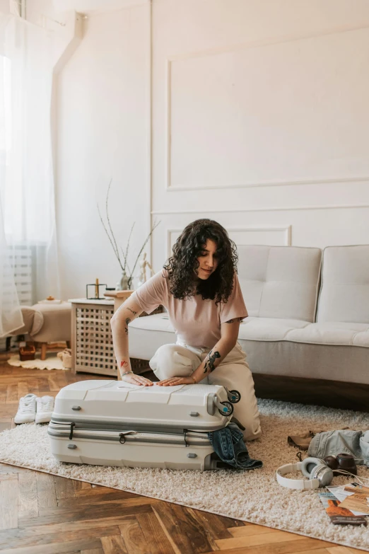 a woman in pink shirt sitting on a white suitcase