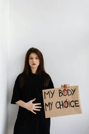 a young woman holds a sign that says, my body is my choice