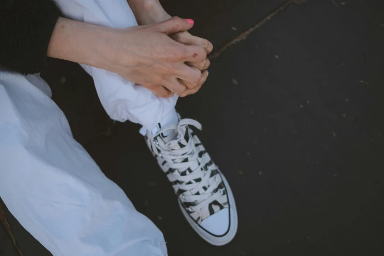 two women holding hands wearing all white converse sneakers