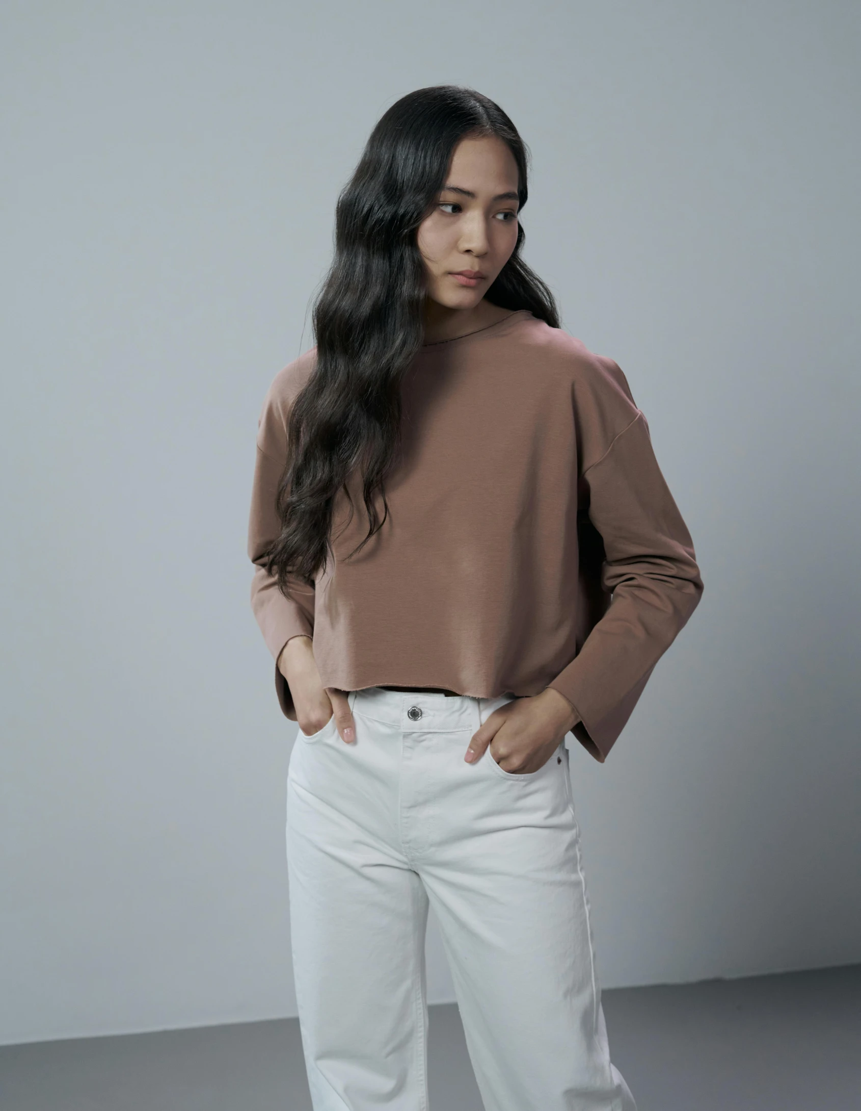 a woman posing with long hair wearing a brown sweater