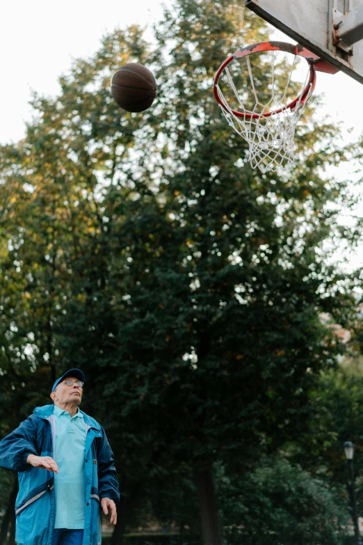 a man playing basketball near a hoop in a city park