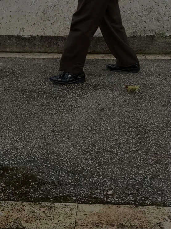 man with an umbrella walking on sidewalk next to wall