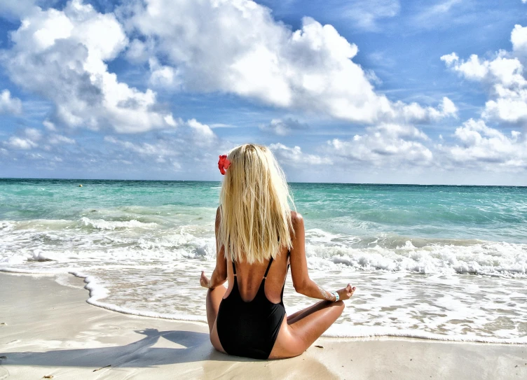 a woman in a body suit sitting on the beach