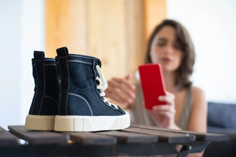 a woman is playing with a phone and wearing sneakers