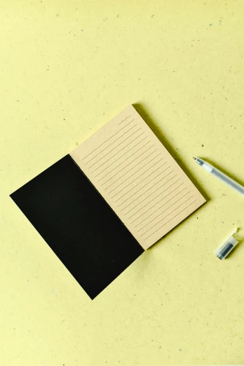 a paper note and pen laying on a yellow surface