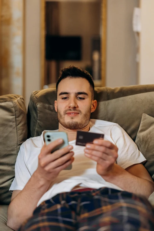 man with cell phone sitting on a couch looking at the screen