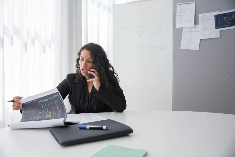 a woman is sitting at her desk and reading on her cell phone