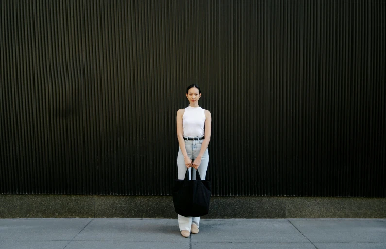 a woman standing next to a wall on top of a sidewalk