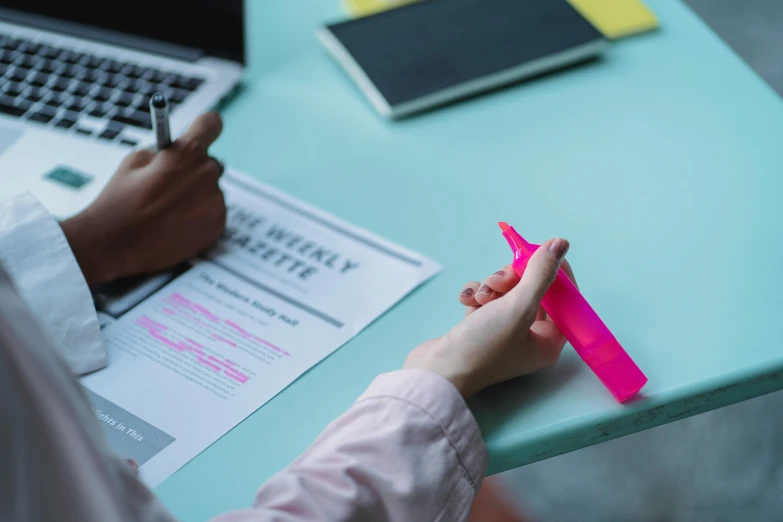 someone is putting pink papers on top of a laptop