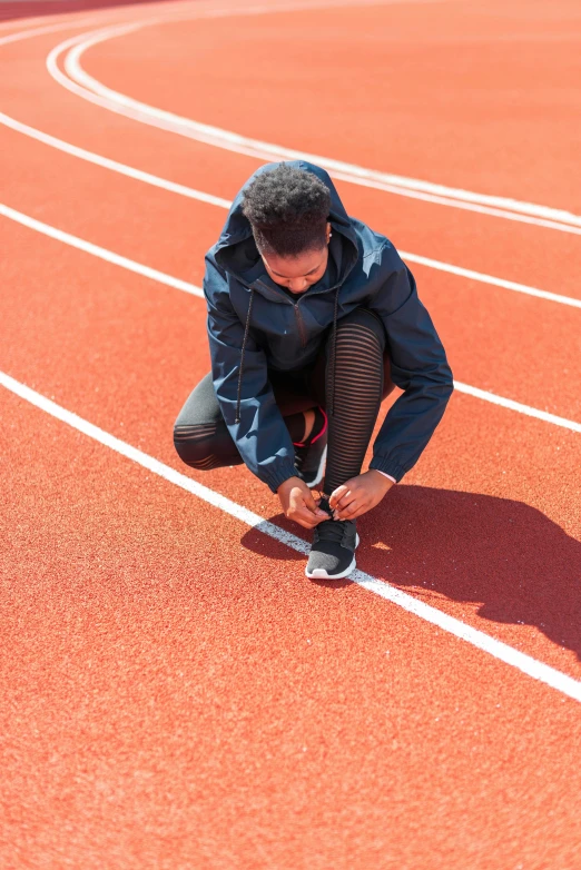 a person kneeling down at the edge of a running track