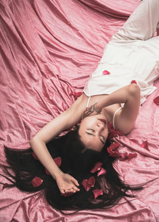 a woman laying on top of a bed wearing a dress and holding onto the bed