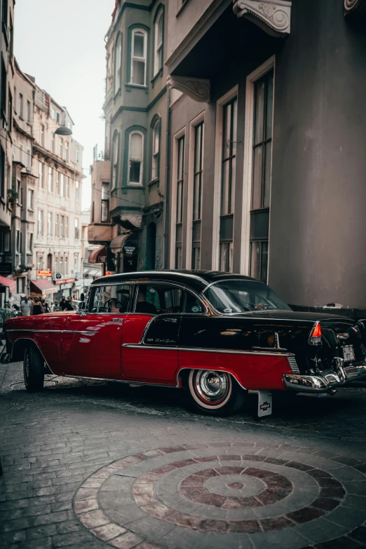 an old vintage car is parked in front of some older buildings