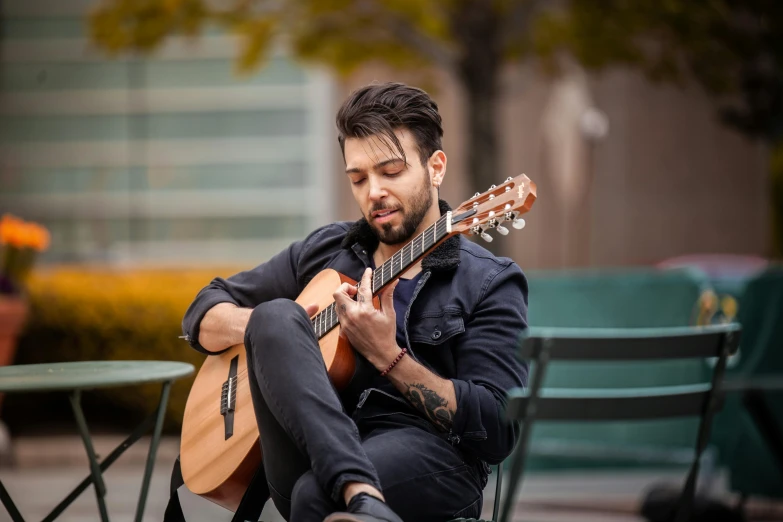 a man sitting in a chair and playing a guitar