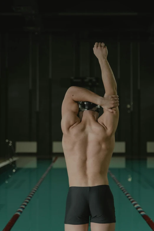 a shirtless man in his underwear in front of an aqua swimming pool