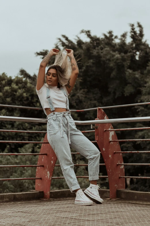 the woman is posing on a rail wearing blue jeans