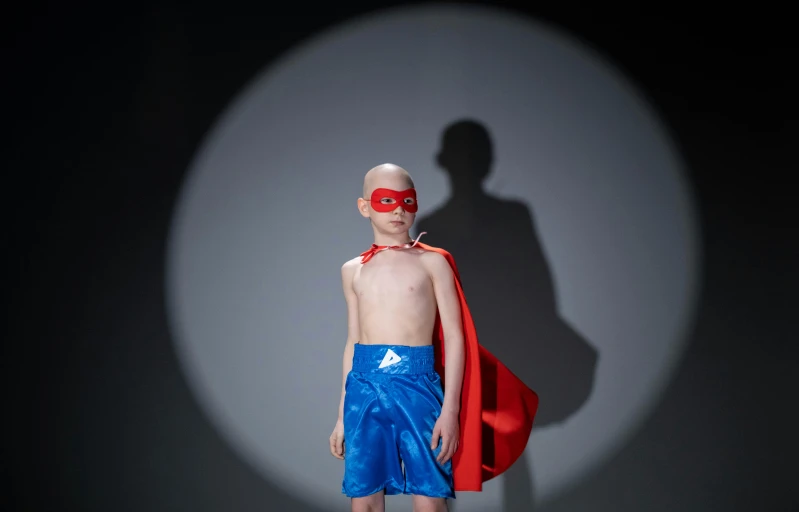 a  standing on a runway in a red mask and blue swimsuit