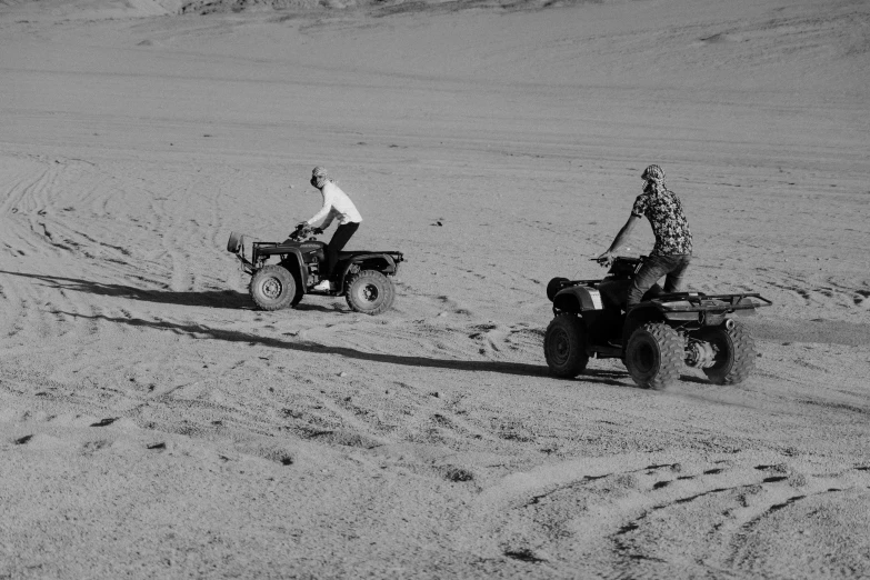 two men on four wheelers playing on the beach