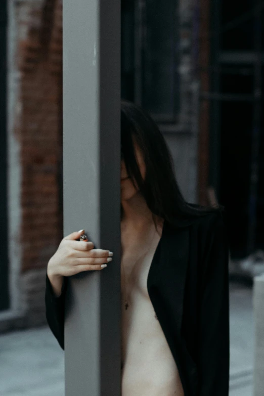 a shirtless woman standing near a pole on a street