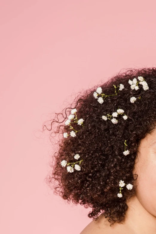 a woman with short curly hair has a small flowered piece of hair in the middle