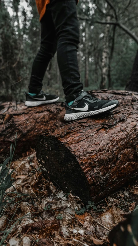 the feet of a person walking on top of a log in the woods